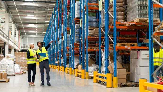 Deux professionnels collaborant dans un environnement de fabrication, illustrant l'objectif d'une mise en œuvre réussie de logiciels pour améliorer l'efficacité opérationnelle.
